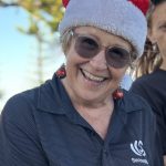 Social Worker Kerry Hawkins is wearing a Christmas hat and is with SensesWA customers at Busselton for a Christmas party.